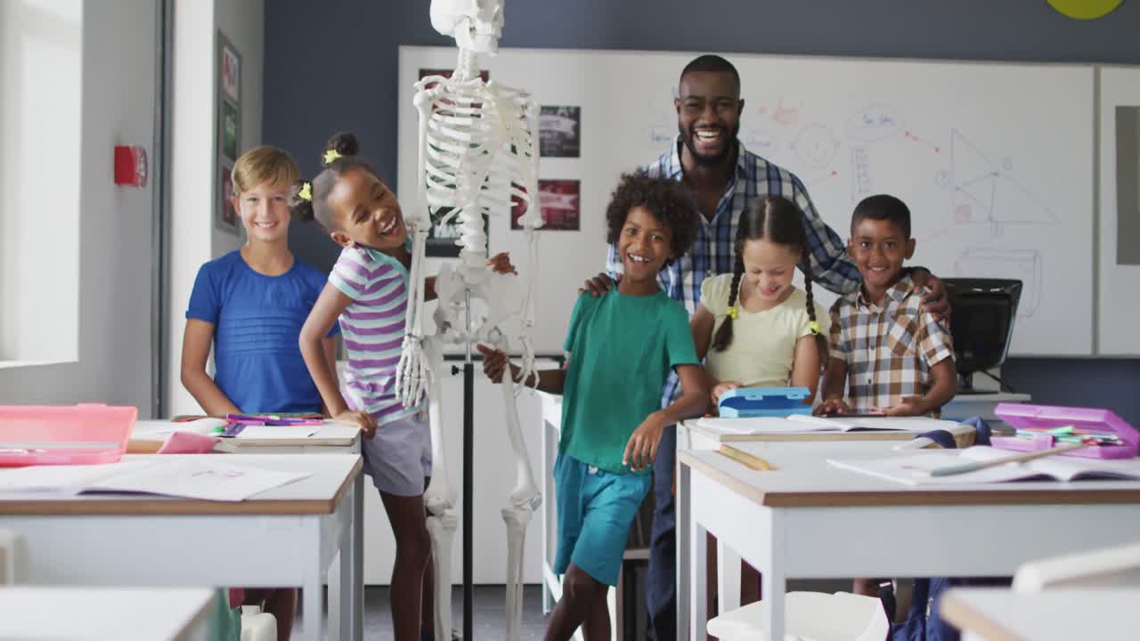 Video of happy african american teacher with class of diverse pupils during anatomy lesson