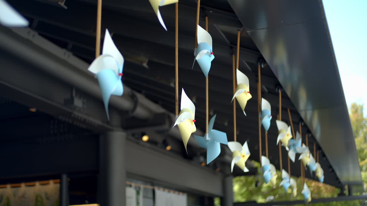Wind blowing through the paper windmills hanging off the side of the rooftop in Kyoto, Japan soft lighting in summer