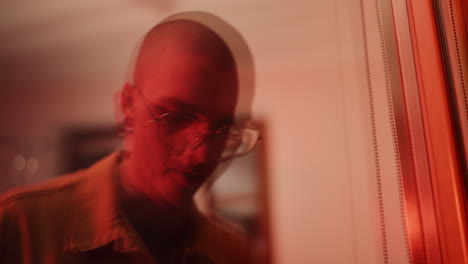 close-up portrait of a person with glasses under red light