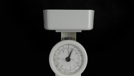 White-kitchen-weighing-scales-against-a-black-background