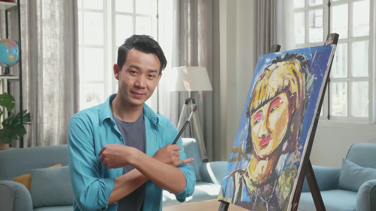 Medium Shot Of An Asian Artist Man Holding Paintbrush Mixed Colour Wipe The Sweat Before Crossing His Arms And Smiling After Finish Painting A Girl On The Canvas