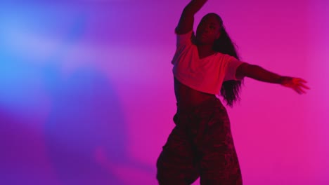 studio shot of young woman dancer dancing against blue and pink lit background 16