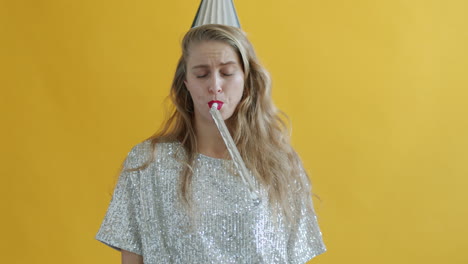 woman blowing a party horn, looking unhappy