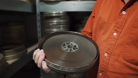 a man opens an old metal round box with an old film strip inside