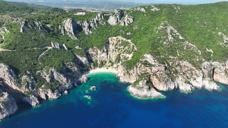 Toma-Aérea-De-La-Playa-De-Giali-En-La-Isla-De-Corfú,-Grecia-Con-Aguas-Cristalinas-De-Color-Turquesa-Y-Acantilados-Escarpados,-Día-Soleado