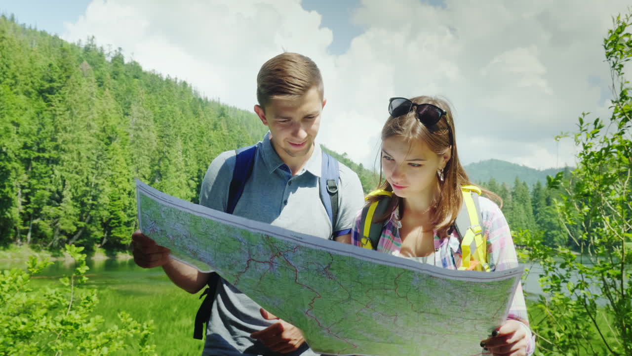 туризм и активный образ жизни молодая пара смотрит на карту стоит в живописном месте в летнее время