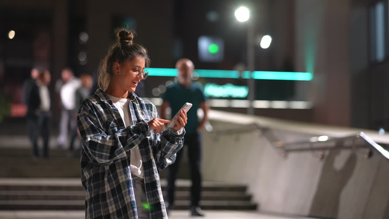 도시에서 밤에 스마트폰을 사용하는 젊은 여성