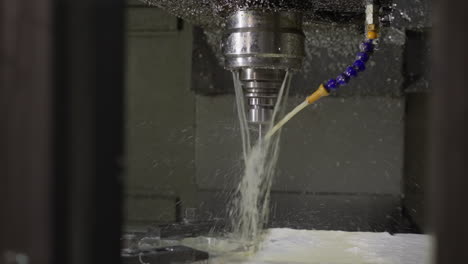 máquina cnc en funcionamiento con pulverización de refrigerante, creando una niebla sobre la superficie del metal