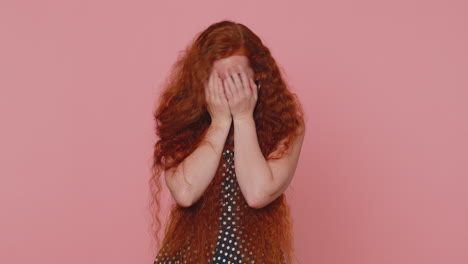 Curious-young-redhead-woman-closing-eyes-with-hand-and-spying-through-fingers,-hiding-and-peeping