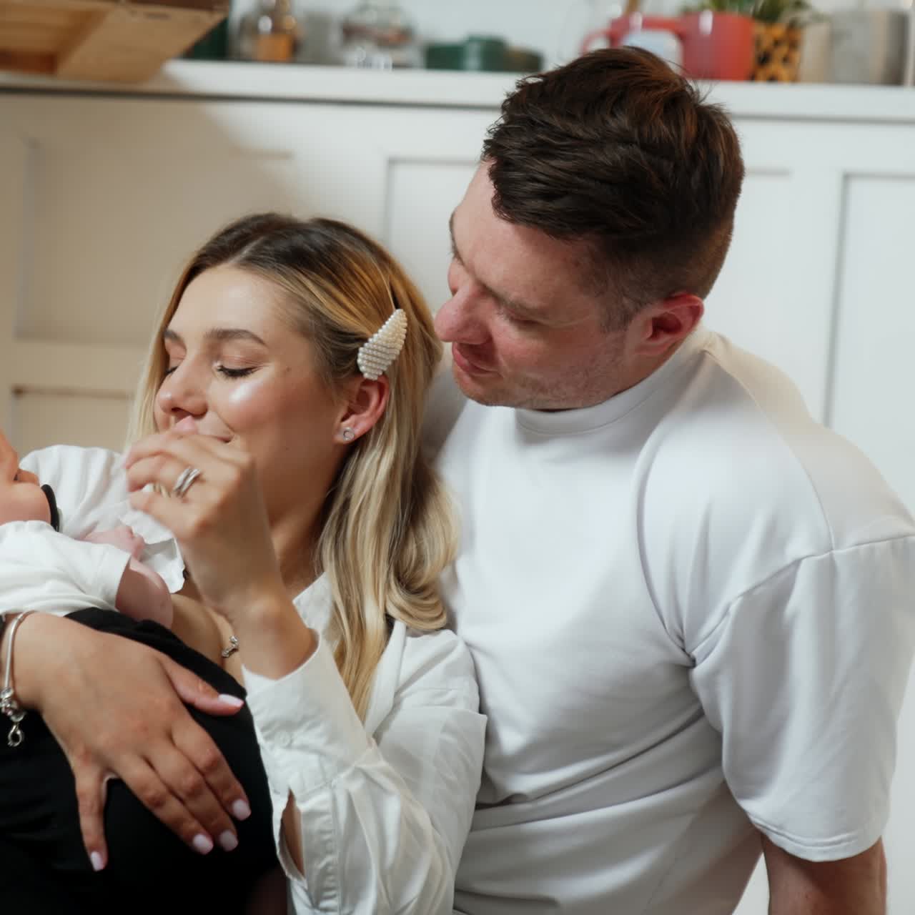 Una famiglia giovane e felice con un neonato che si scambia affettuosi abbracci. Adorabile neonato, una nuova famiglia.