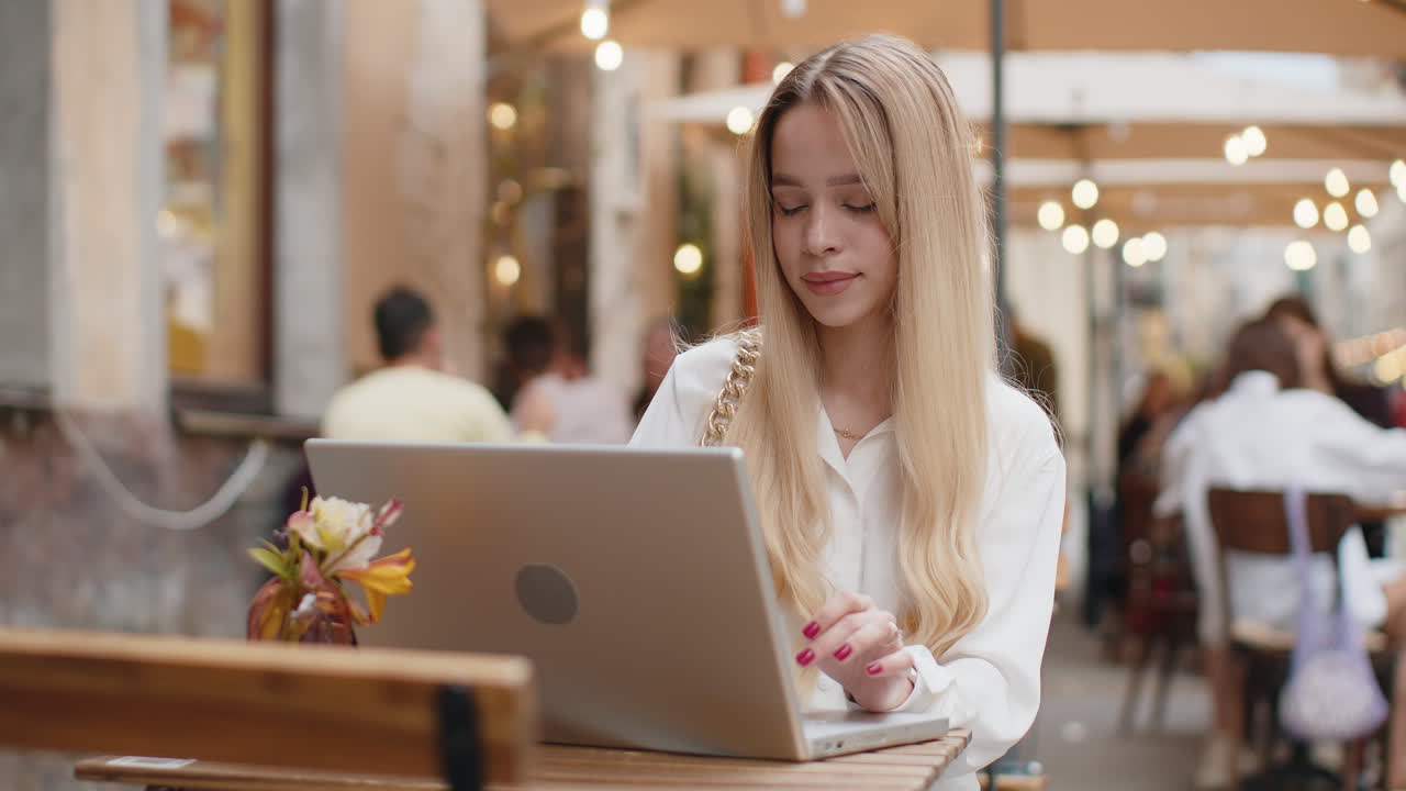 Donna che lavora online a distanza con il portatile in un caffè o ristorante della città, navigando sul sito web, chattando