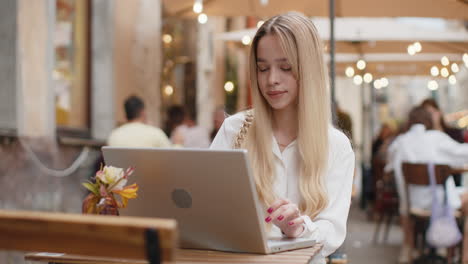 mujer trabajando en línea trabajo remoto con computadora portátil en la ciudad café o restaurante navegando por el sitio web chateando