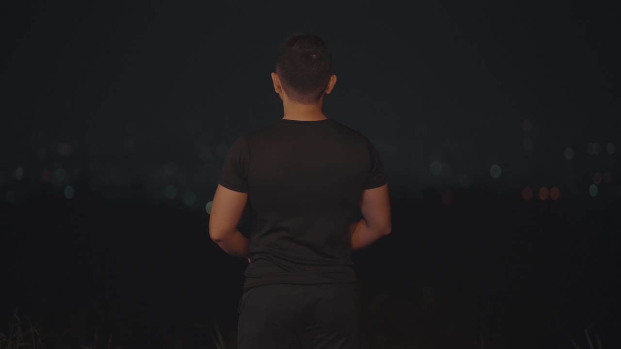 Man Standing at Night Overlooking City Lights with Bokeh Background