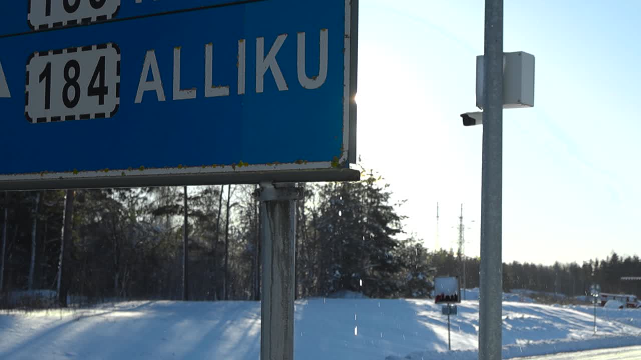 Traffic sign during winter sunny day while snow is melting on the sign and dripping down on it creating water splatter and drops in slow motion. Sun is shining behind the sign and has sun beams.