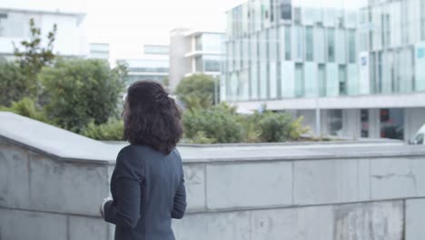 mujer de negocios seria en traje caminando arriba a su edificio de oficinas