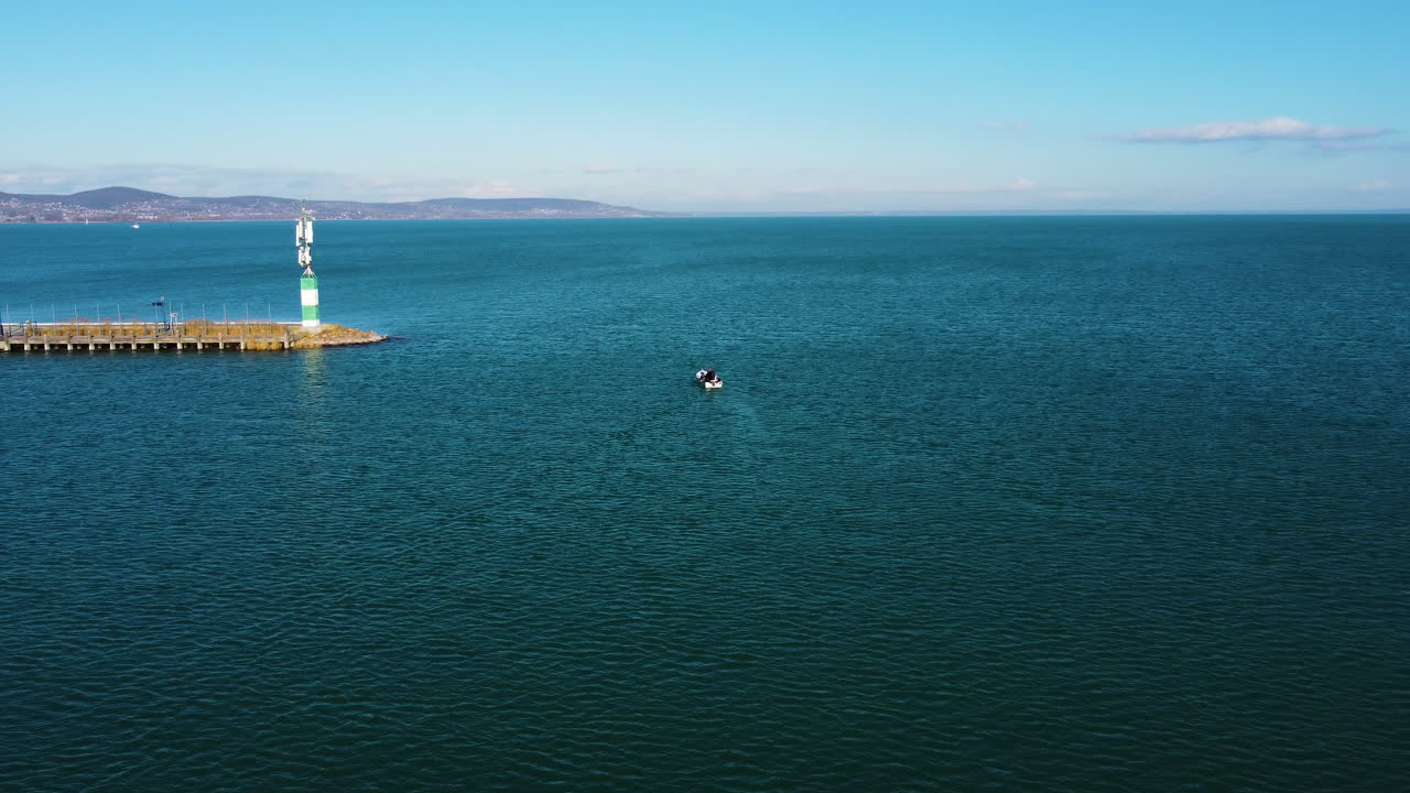 Establishing drone view of Lake Balaton with boat trails forming lines across blue open water