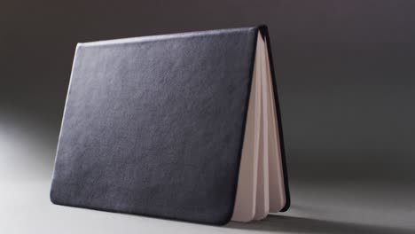 close up of open black book standing horizontal with copy space on gray background in slow motion