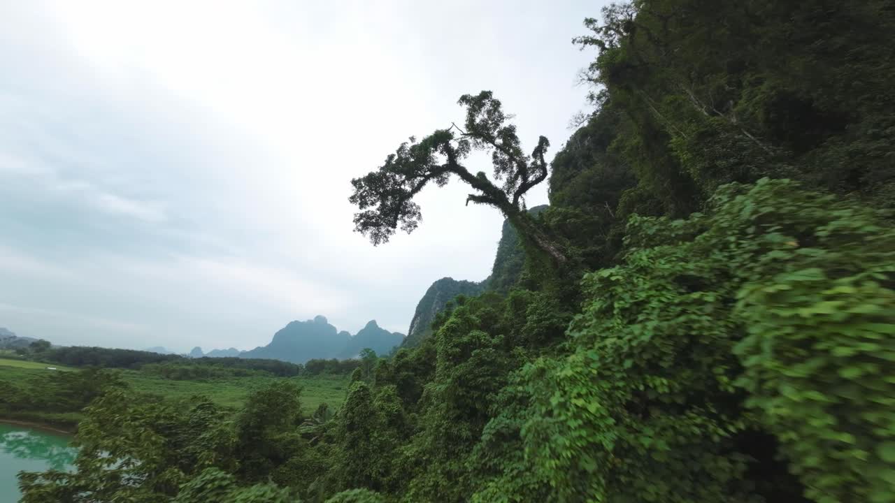 Aerial view over the tranquil waters and green landscape of Blue Lagoon, Laos, surrounded by high cliffs, rise between overhanging trees