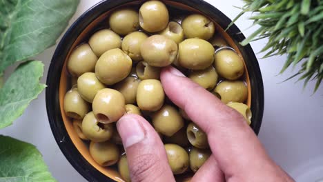 hand picking green olives from a bowl