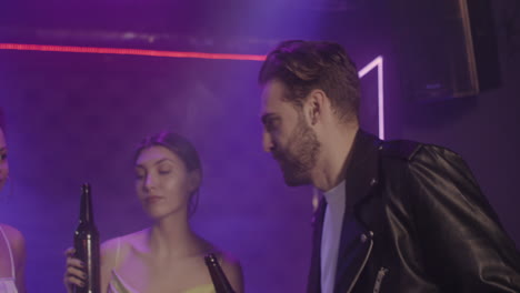 group of four young friends toasting with beer bottle while dancing at disco 1