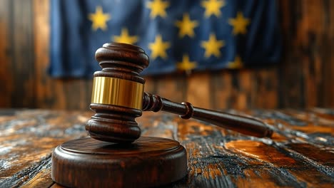 gavel on table with flag. a wooden gavel sits on a polished table with a blue flag of stars hanging in the background, symbolizing justice.