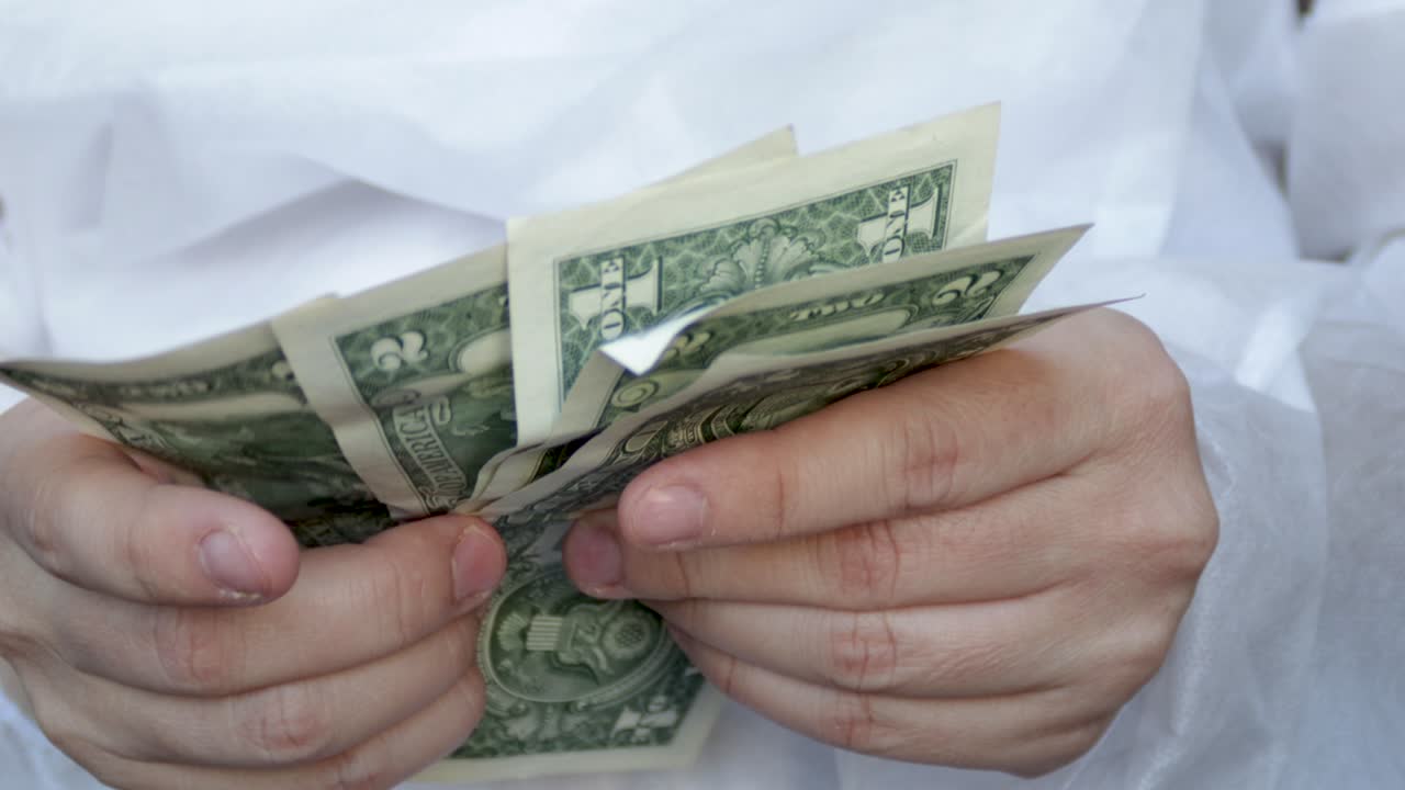 el médico o la enfermera está contando algunos billetes de dólar.