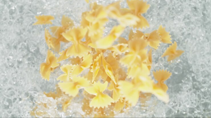 Farfalle Pasta Falling Into Pot Of Boiling Water Making A Splash In Slow Motion, Table Top View