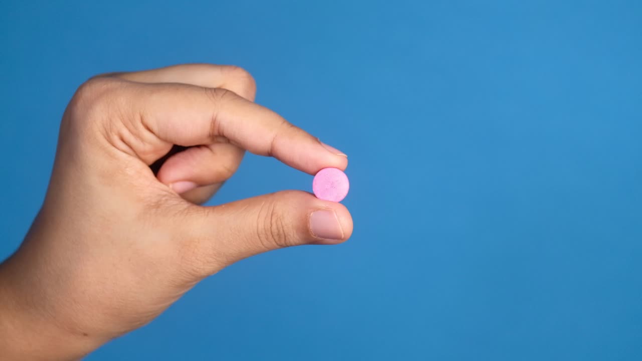 píldora rosada en la mano