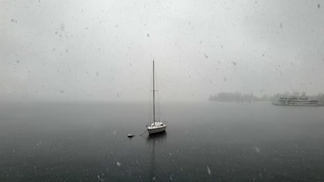 Hermoso-Disparo-único-De-Nieve-Cayendo-Sobre-El-Lago-Maggiore-Y-Barco-Amarrado,-Italia