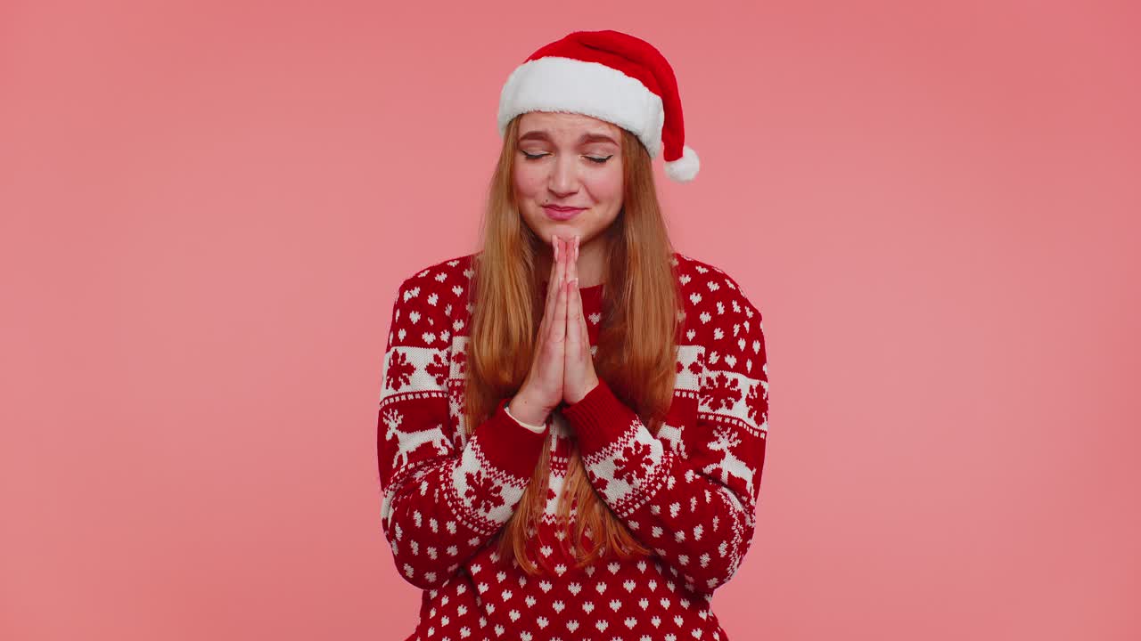 Girl in christmas santa sweater praying looking upward making wish asking with hopeful expression