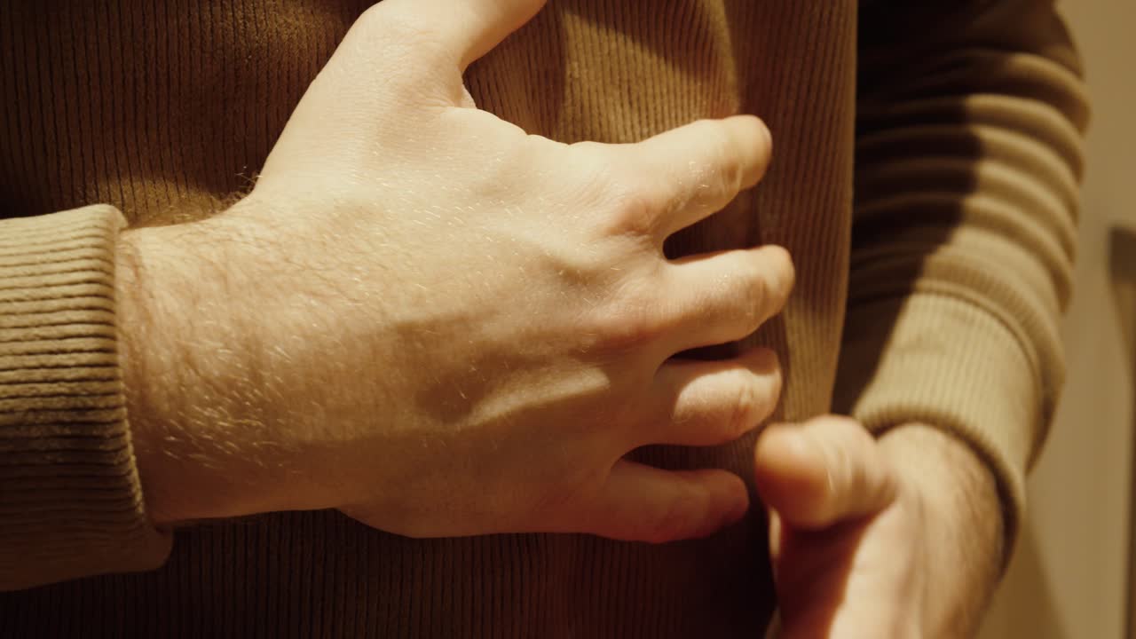 Close-up of a man holding his stomach in pain. Concept of abdominal pain, digestive problems, health issues, illness symptoms, and discomfort