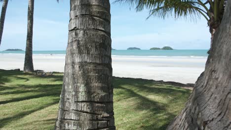 palm tree trunks and white sand beach with islands on koh chang island