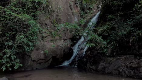 Movimiento-De-Deslizamiento-Lateral-Que-Muestra-Una-Cascada-En-El-Bosque-Tropical-De-Montaña-Dentro-De-La-Ciudad-De-Río-De-Janeiro-Que-Revela-Un-Entorno-Más-Amplio-Con-Un-Pequeño-Estanque