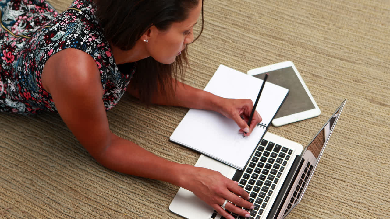 mujer ejecutiva usando una computadora portátil mientras escribe en un diario 4k