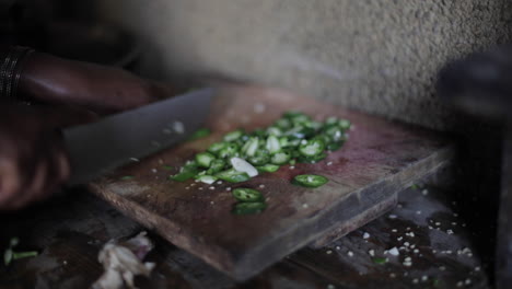 african woman chopping jalapeno peppers on wooden cutting board