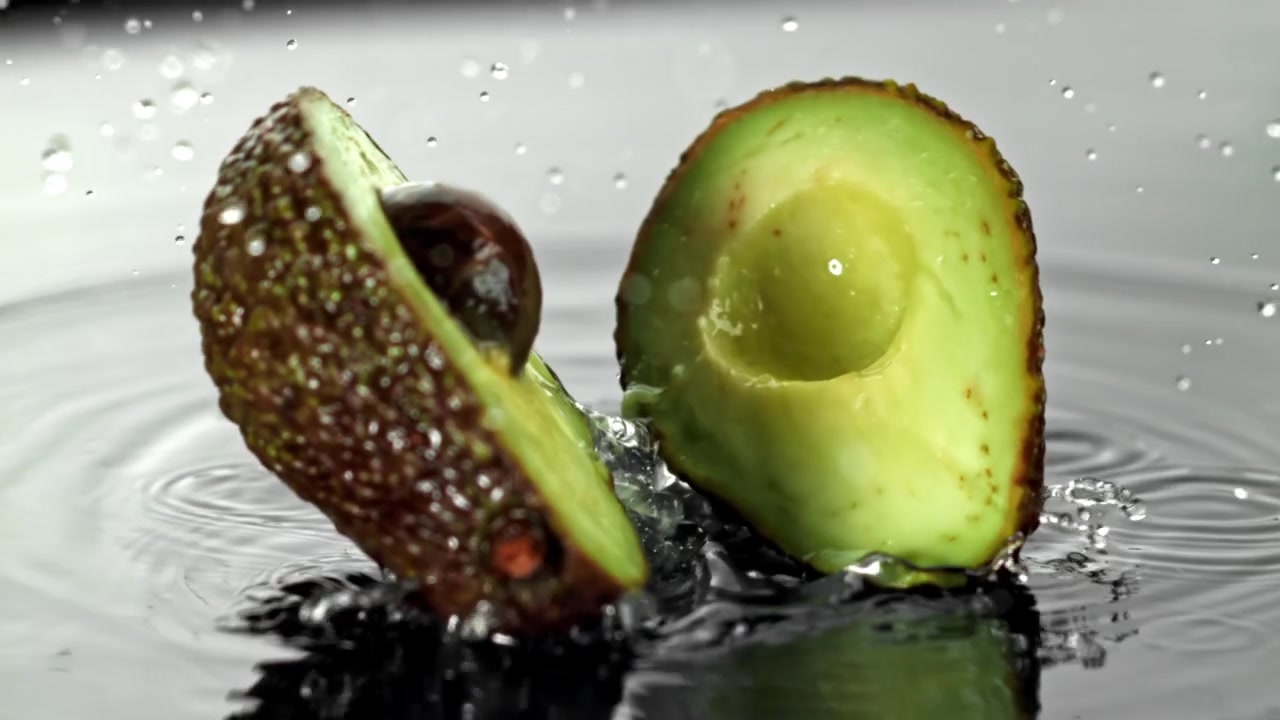 Metà di avocado che schizzano nell'acqua al rallentatore