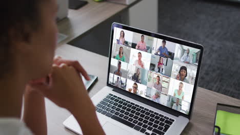 african american woman having a video conference on laptop with office colleagues at office