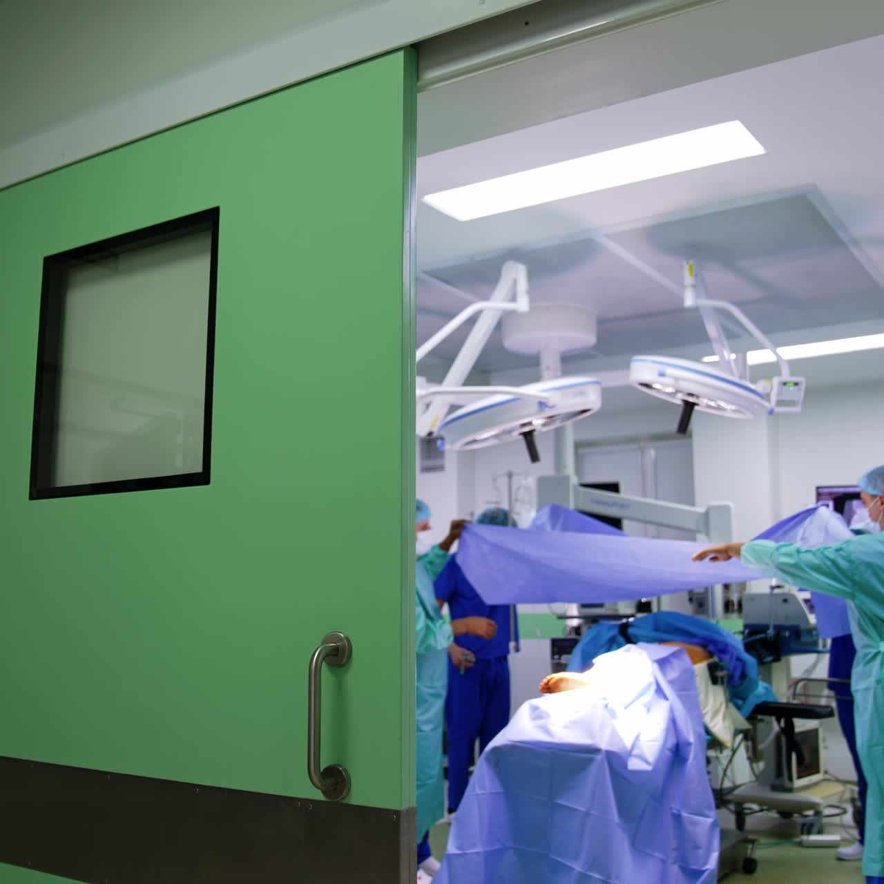 Médicos cubren al paciente con una tela azul al inicio de la cirugía. Preparación para una operación ortopédica