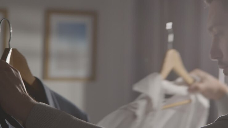Young Man At Home Choosing Business Suit From Clothes Rail For Job Interview 2