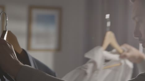 young man at home choosing business suit from clothes rail for job interview 2