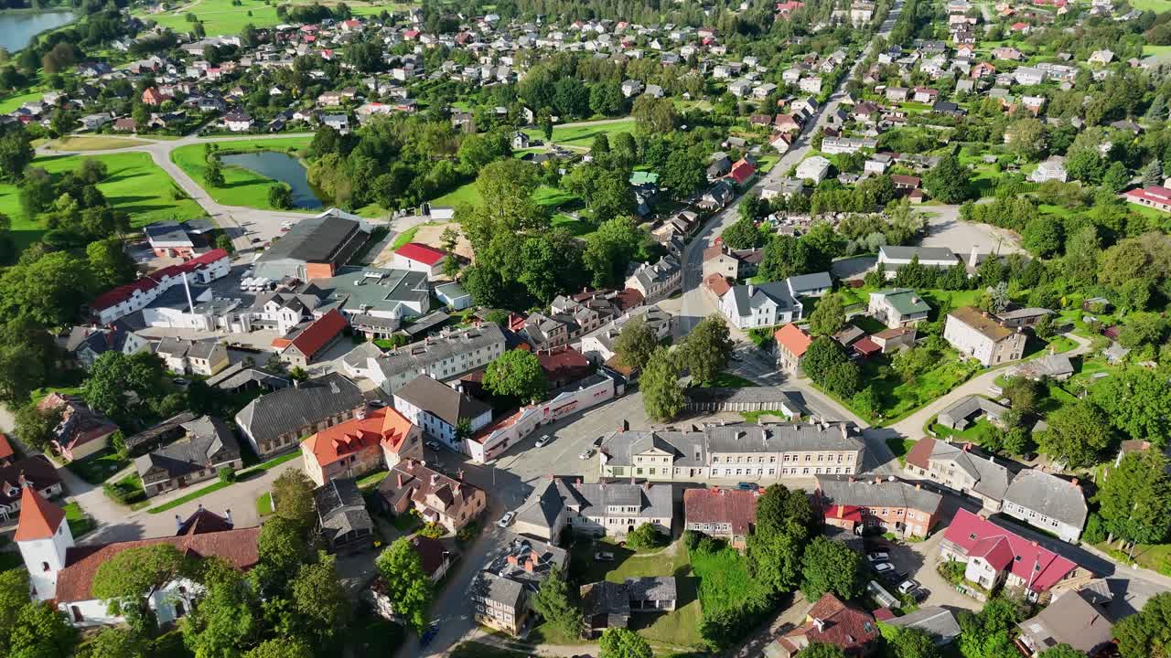 Aerial view revealing Talsi's charming Latvian landscape, showcasing historic buildings, verdant surroundings, and tranquil setting bathed in sunlight, drone establishing shot