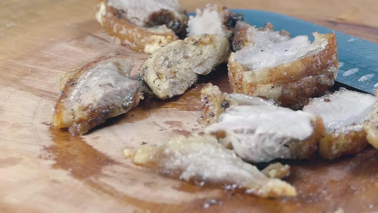 나무 도마 위의 칼 옆에 잘게 잘린 바삭바삭한 삼겹살 돼지고기의 내부 슬라이더 샷