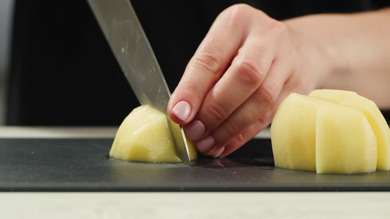 Woman cutting potato on table in kitchen. High quality 4k footage