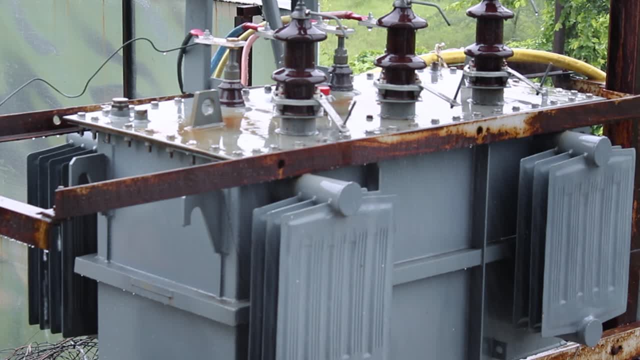 Rain hitting power transformer during monsoon in rural area. Perfect for energy, utility or weather themes