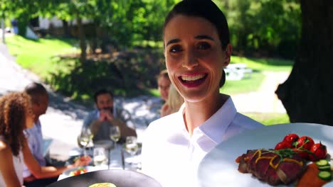 Smiling-waitress-with-food-plate-at-restaurant