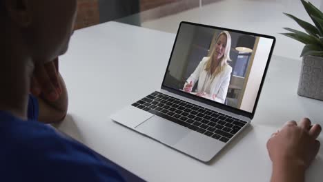 African-american-woman-talking-on-video-call-on-laptop-with-female-office-colleague-at-home