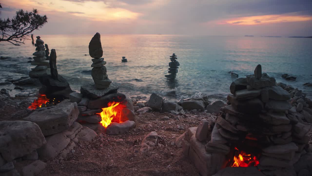 Cinemagraph of artistic stone fire ovens with burning flames and towers on Croatian beach by the sea