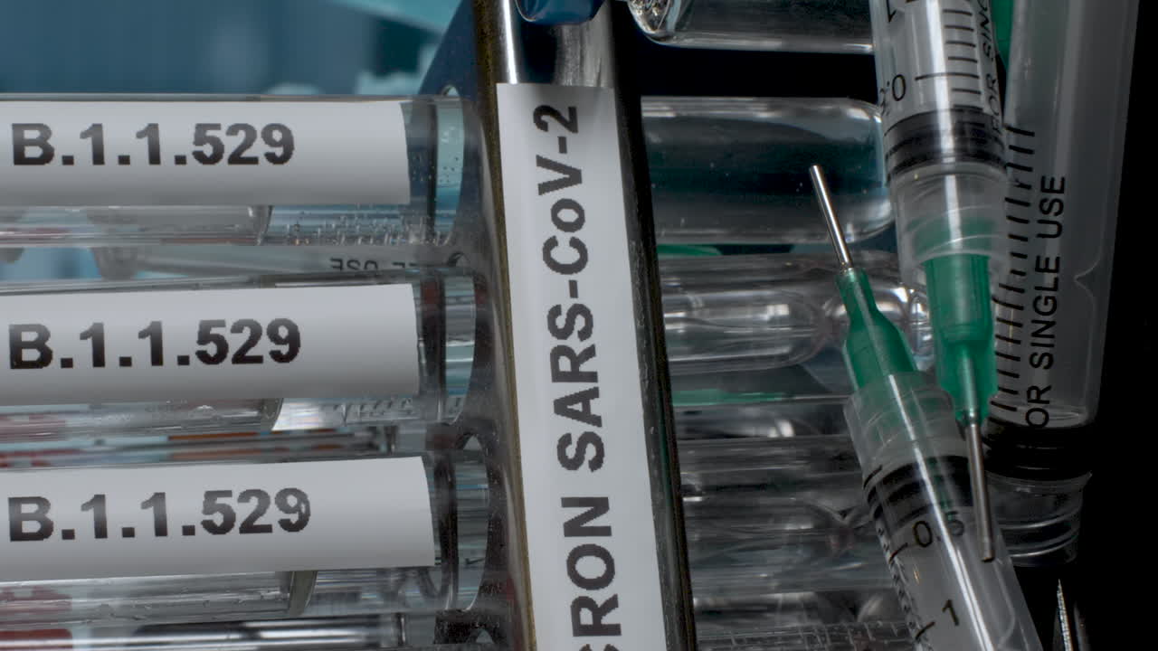 An extreme close up vertical video panning across a rack containing several medical test tubes labelled Omicron B.1.1.529, as the new strain of Covid 19 pandemic raises healthcare concerns globally