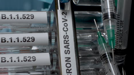 an extreme close up vertical video panning across a rack containing several medical test tubes labelled omicron b.1.1.529, as the new strain of covid 19 pandemic raises healthcare concerns globally