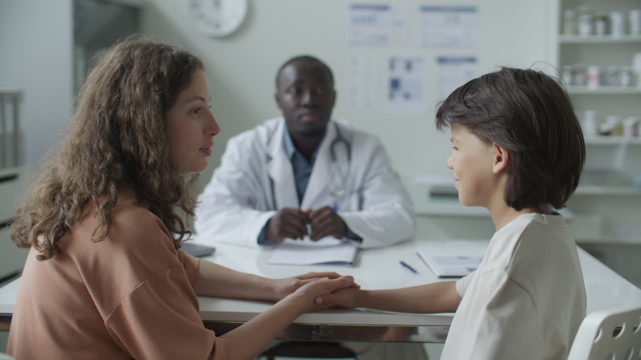 Loving Mother Comforting Young Son during Medical Appointment in Clinic